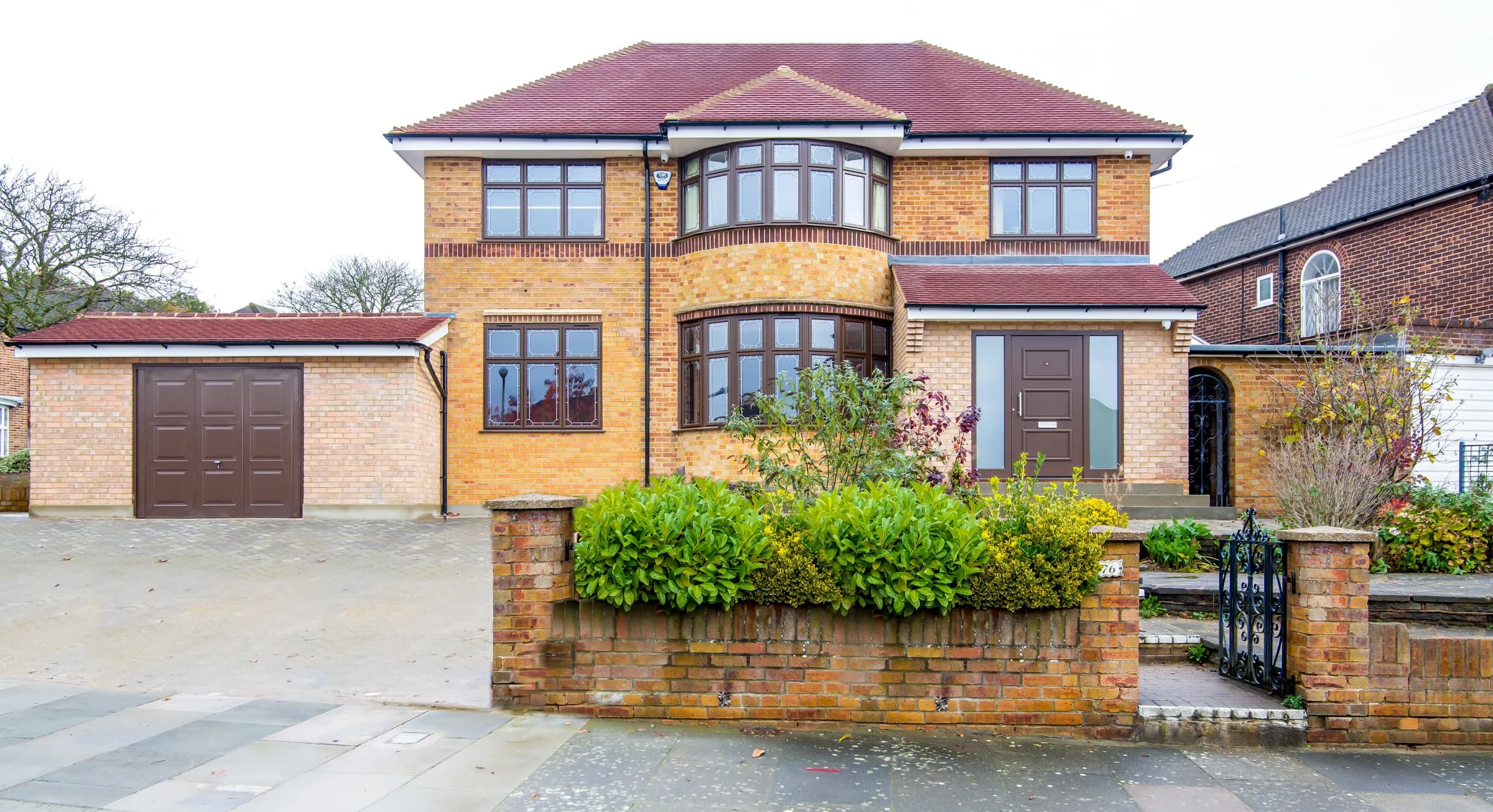 Front elevation of the Northiam Road new-build house: buff brick, hipped clay-tile roof, two-storey bow window and detached garage